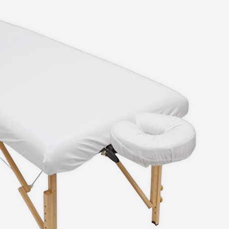 Spa massage table covered with white massage sheets.