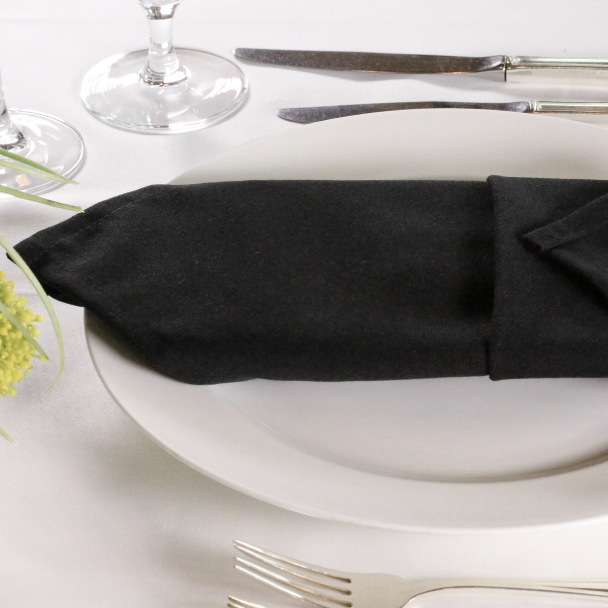 Black lieberspun napkins folded on a plate in a dressed up restaurant table