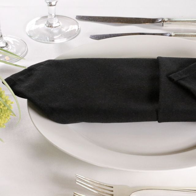 Black lieberspun napkins folded on a plate in a dressed up restaurant table
