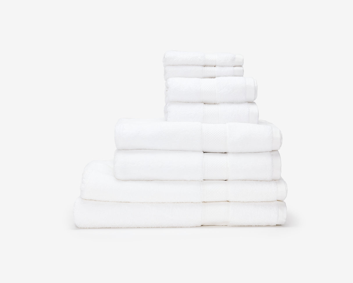 White hotel towels folded and placed on top of each other to form a pile.