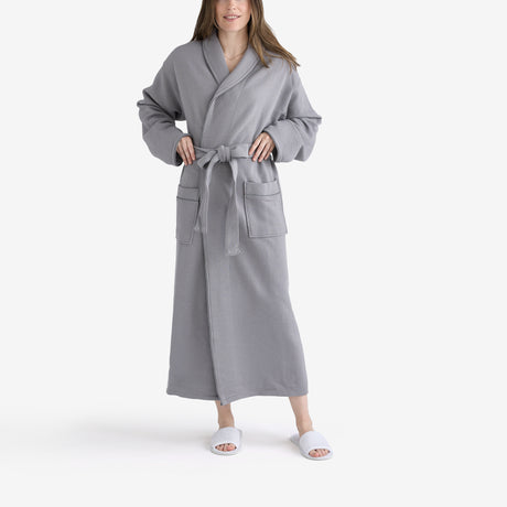 Women wearing a grey hotel bathrobe and white slippers.
