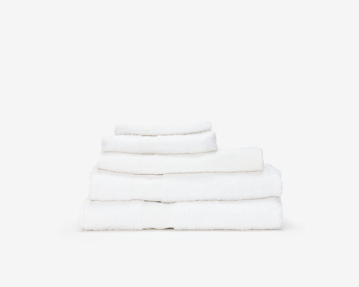 Folded white hotel towel placed on top of each other to form a pile.