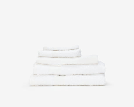 Folded white hotel towel placed on top of each other to form a pile.