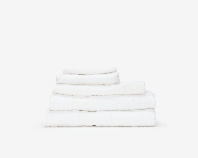Folded white hotel towel placed on top of each other to form a pile.
