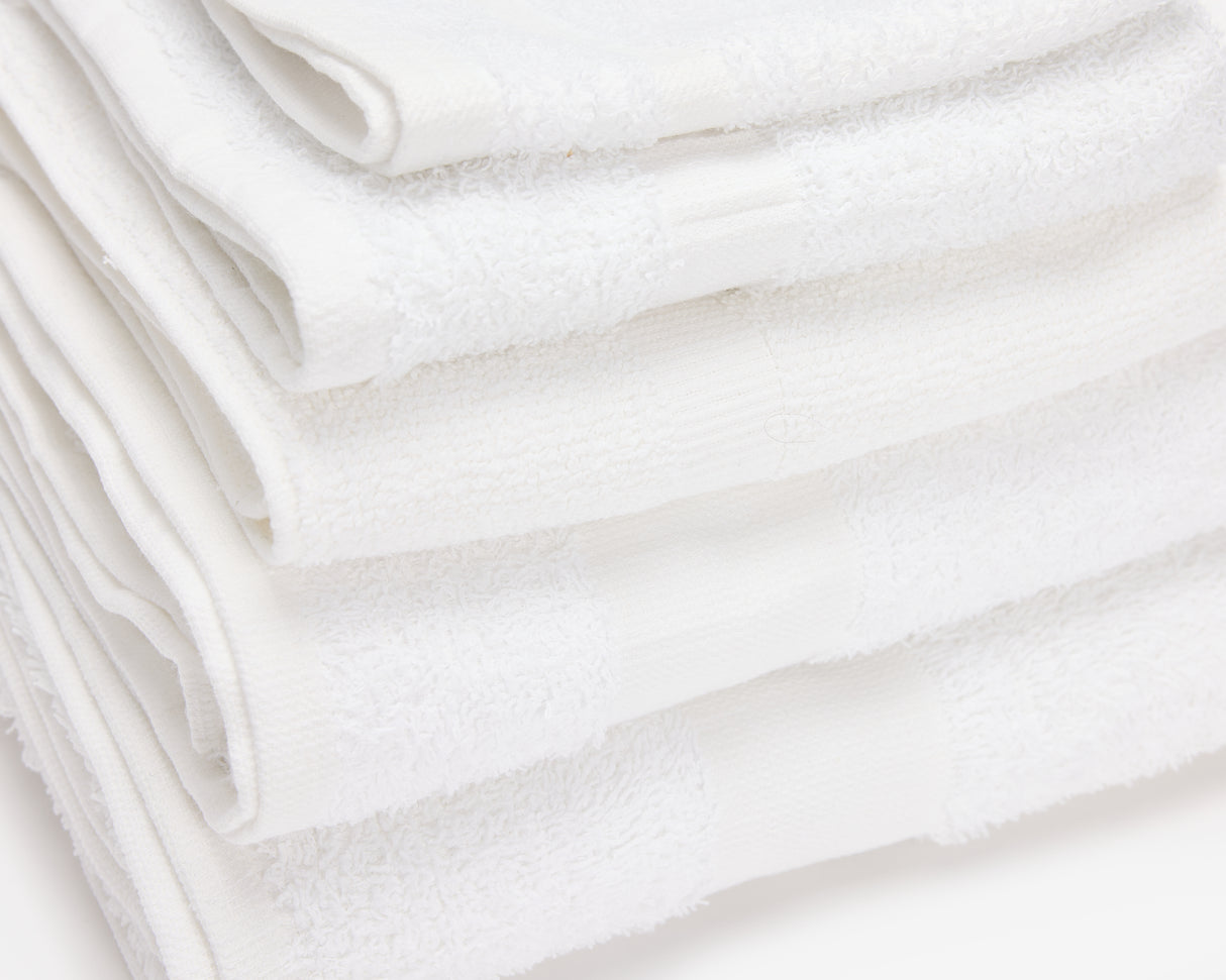 Folded white hotel towel placed on top of each other to form a pile.
