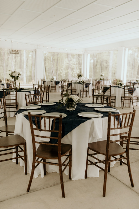 Restaurant dining room, round tables with white tablecloth, brown chairs.  