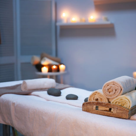 Picture of a SPA with a massage table, white towels, rocks and candles.